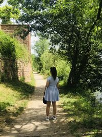 Rear view of woman walking on footpath in park