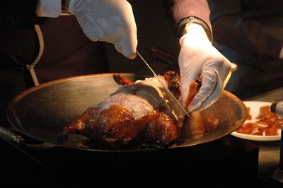 Midsection of person carving peking duck 