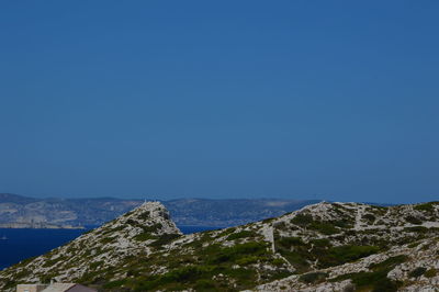 Scenic view of sea and mountains against clear blue sky