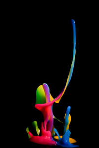 Close-up of multi colored splashing water against black background