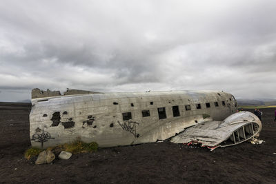 Damaged airplane on beach against sky