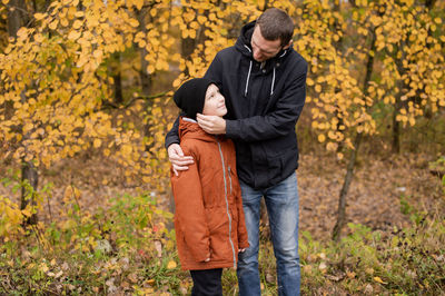 Dad hugs his son and adjusts his hat on the street