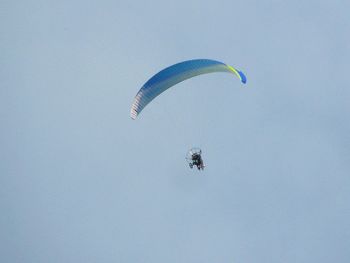 Low angle view of woman paragliding in blue sky