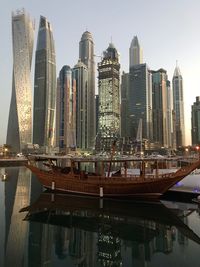 Modern buildings by river against sky in city