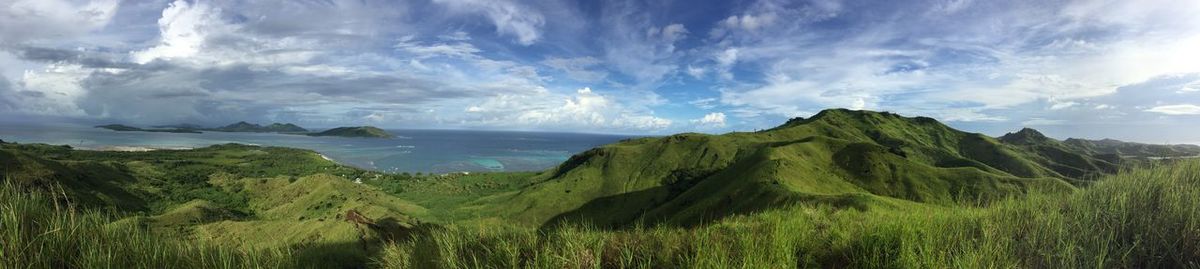 Panoramic view of field and sea against sky