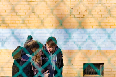 Young woman standing against wall