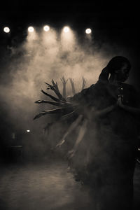 Woman standing in illuminated water at night