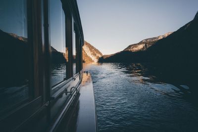 Cropped image of boat sailing in river by mountains