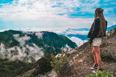 Rear view of man standing on mountain against sky