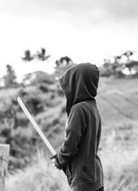 Side view of person holding sword on field