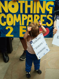 Full length of girl wearing text on paper in city