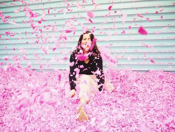 Portrait of woman standing against pink wall
