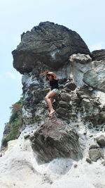 Woman climbing on rock against sky