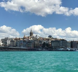 View of buildings by sea against cloudy sky