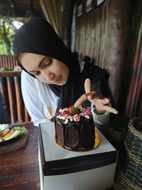 Woman wearing hijab touching cake at restaurant