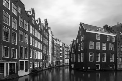 Buildings by canal against sky