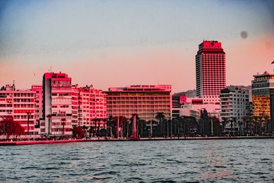 Buildings by sea against sky in city