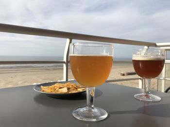 Close-up of beer in glass on table against sea