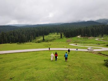 Group of people on grassland against the sky