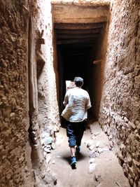 Rear view of man walking in narrow building