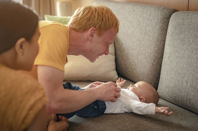 Mother and father playing with toddler on sofa at home