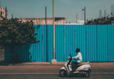 Man riding motor scooter on road