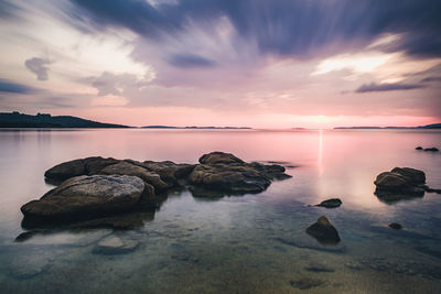 Long expposure rocks on sea against sky during sunrise