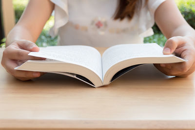 Midsection of woman reading book on table