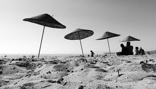 People on sandy beach against clear sky