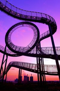 Low angle view of rollercoaster against sky during sunset