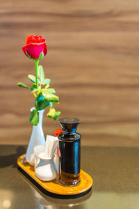 Rose in vase and shakers on tray at restaurant table