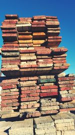 Stack of wooden planks against clear sky