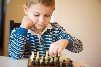 Cute boy playing chess at home