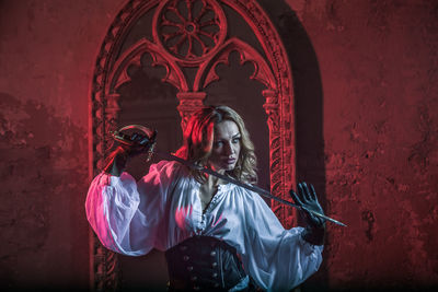 Woman in costume holding sword at abandoned building during night