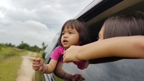 Portrait of mother and daughter against sky