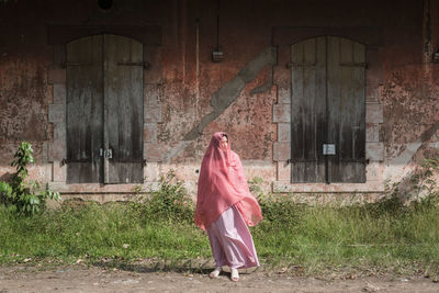 Woman standing by pink building