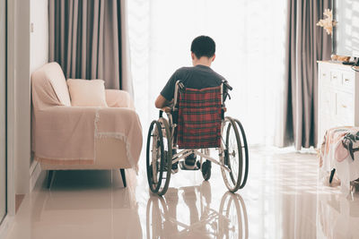 Rear view of man sitting on sofa at home