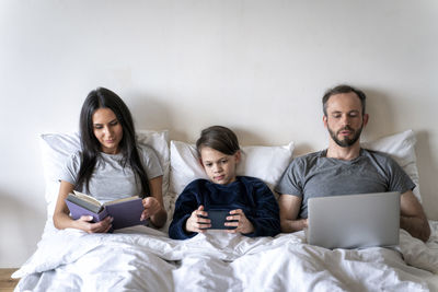 Full length of friends sitting on bed