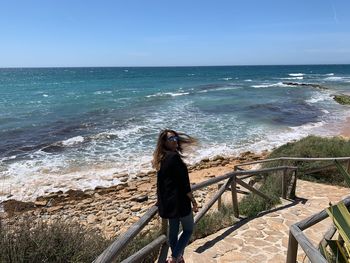 Portrait of woman standing at beach against sky