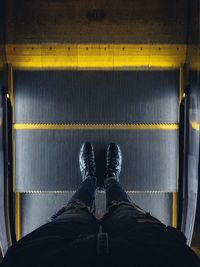 Low section of man standing on escalator