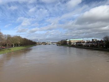 Scenic view of river by buildings against sky