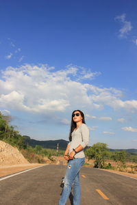Woman standing on road against sky