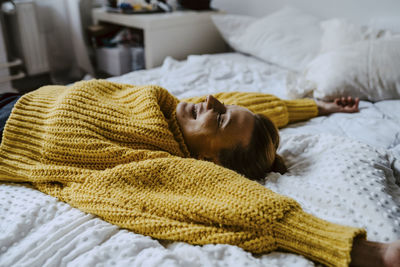 Woman with hand raised lying on bed at home