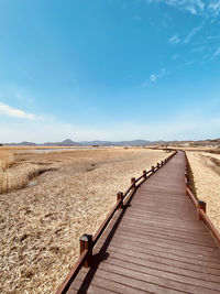 View of boardwalk on landscape against blue sky in korea