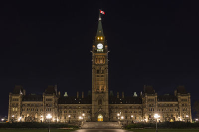 Low angle view of illuminated clock tower at night