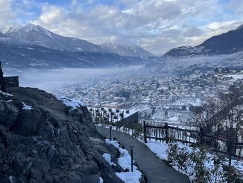 Aerial view of townscape by snowcapped mountain against sky