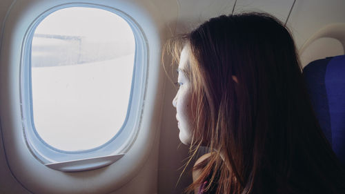 Close-up of woman looking through airplane window