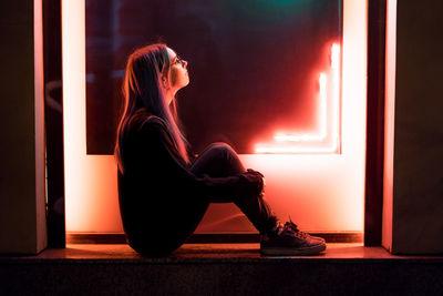 Side view of young woman sitting at home