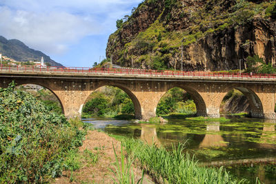 Arch bridge over river against sky