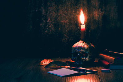 Illuminated candle on human skull over table